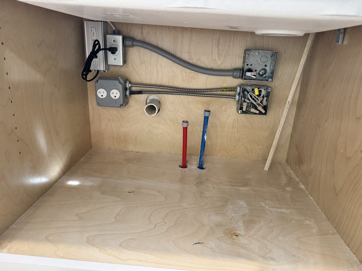 Outlets and junction boxes installed inside a kitchen cabinet with flexible conduit