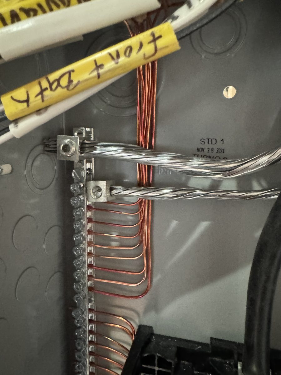 Close up of neatly dressed grounding and neutral terminations inside an electrical panel